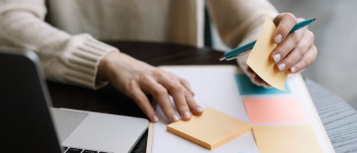 Closeup,Shot,Of,University,Student,Hand,Holding,Pen,,Sticky,Note