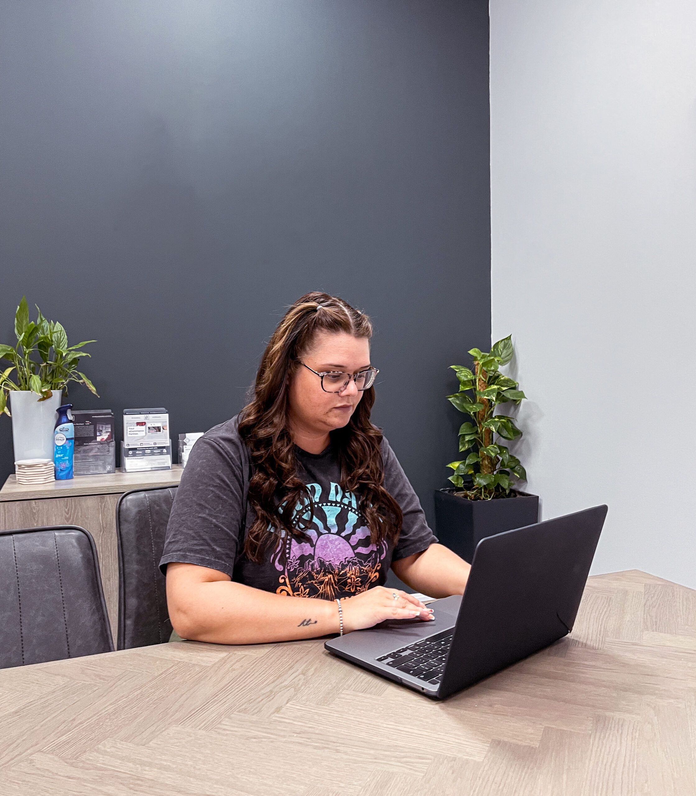 Photograph of Danielle Whittaker sat at a table and using an Apple Macbook